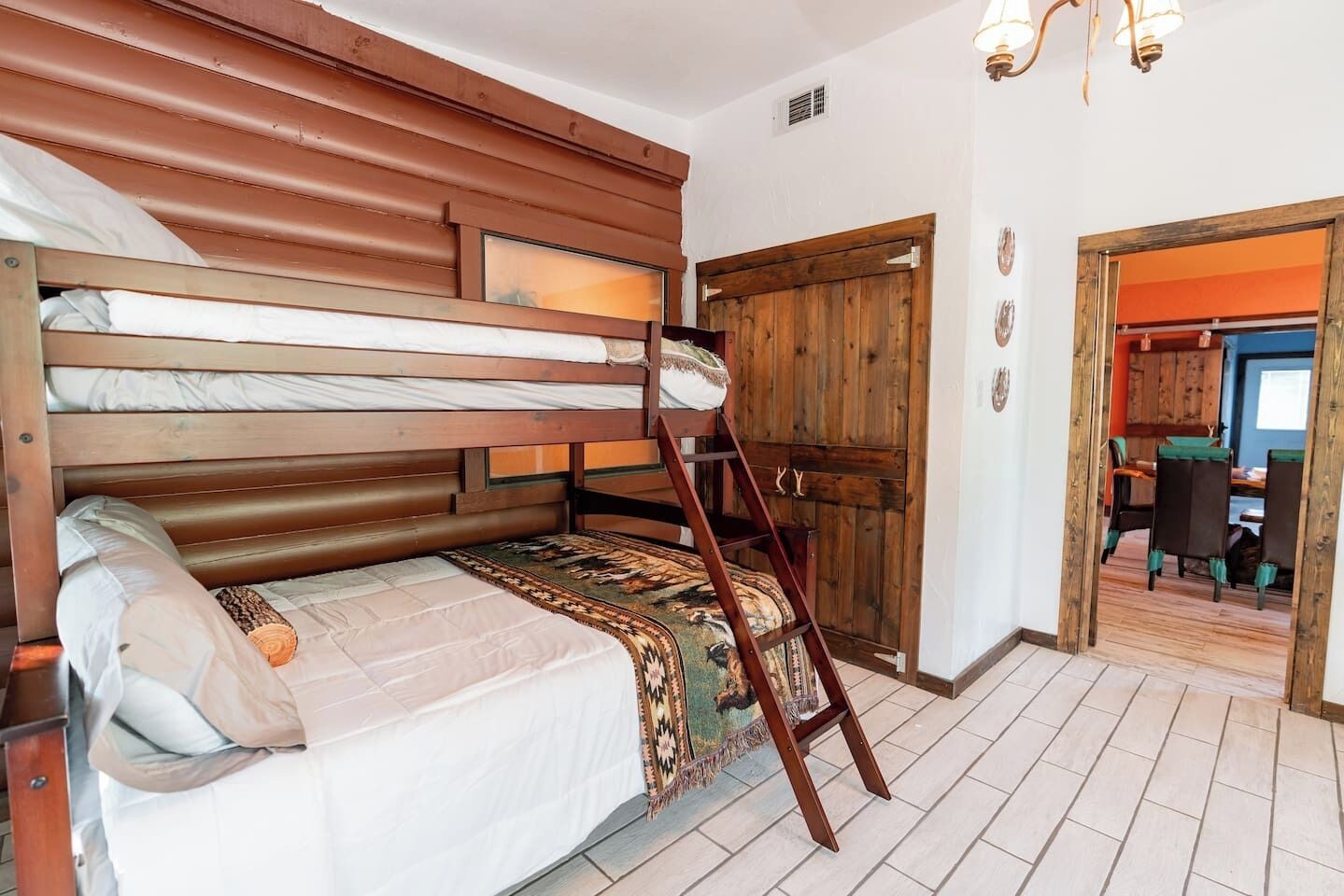 A bunk bed with a ladder, a wooden door, and a small rug.