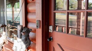A wooden door with a bear sculpture, a keyhole, and a window with a view of trees. - Great family retreat! Pickleball  and pet friendly (Granbury)