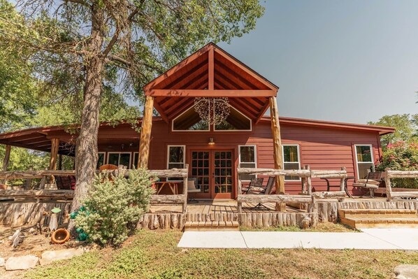 Une cabane rustique avec une véranda en bois, une grande fenêtre et une porte.