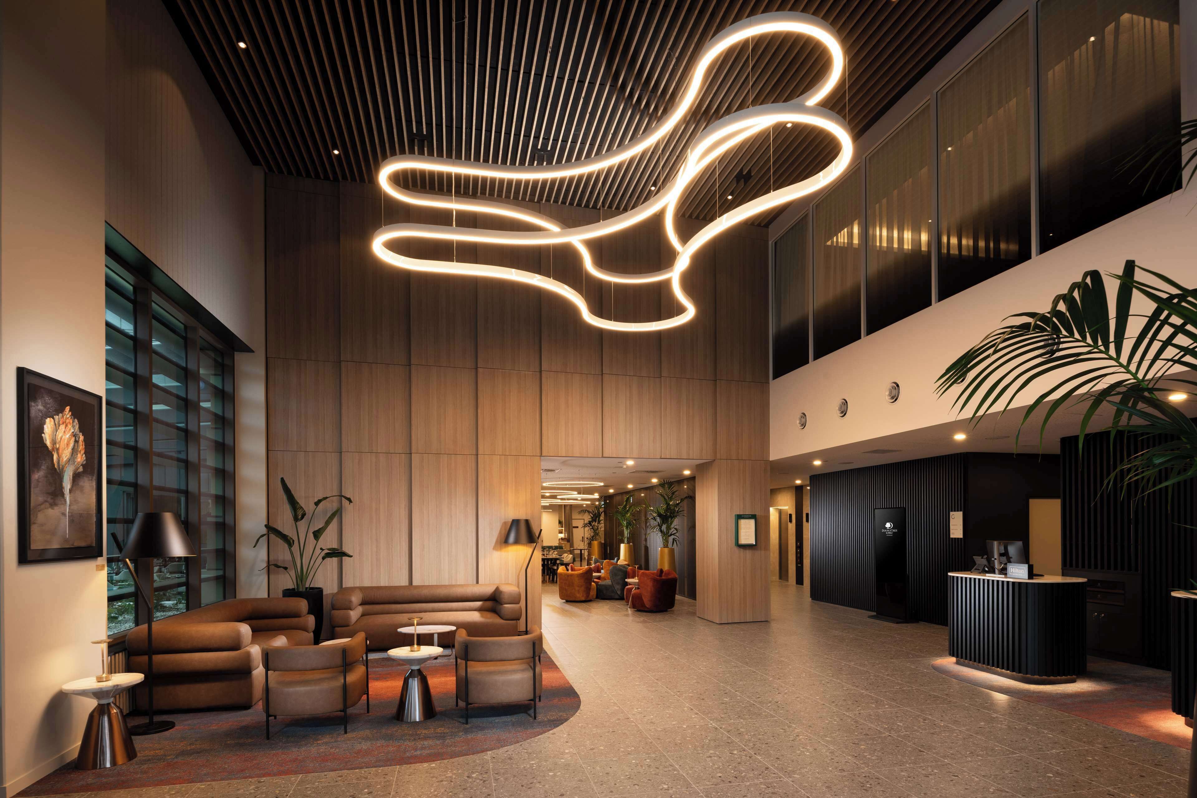 Un hall d’entrée spacieux au design moderne, comprenant un comptoir d’accueil, un espace salon et de grandes fenêtres.