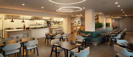 Un restaurante moderno con varias zonas de comedor, incluyendo un bar y asientos con mesas y sillas redondas.
