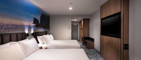 A hotel room with two beds, a large TV, and a mural of a beach scene.