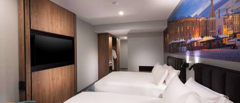 Une chambre d’hôtel avec deux lits, une télévision et une fresque représentant un paysage urbain.