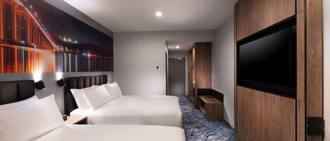 A hotel room with two beds, a TV, a wooden cabinet, and a mural of a bridge.