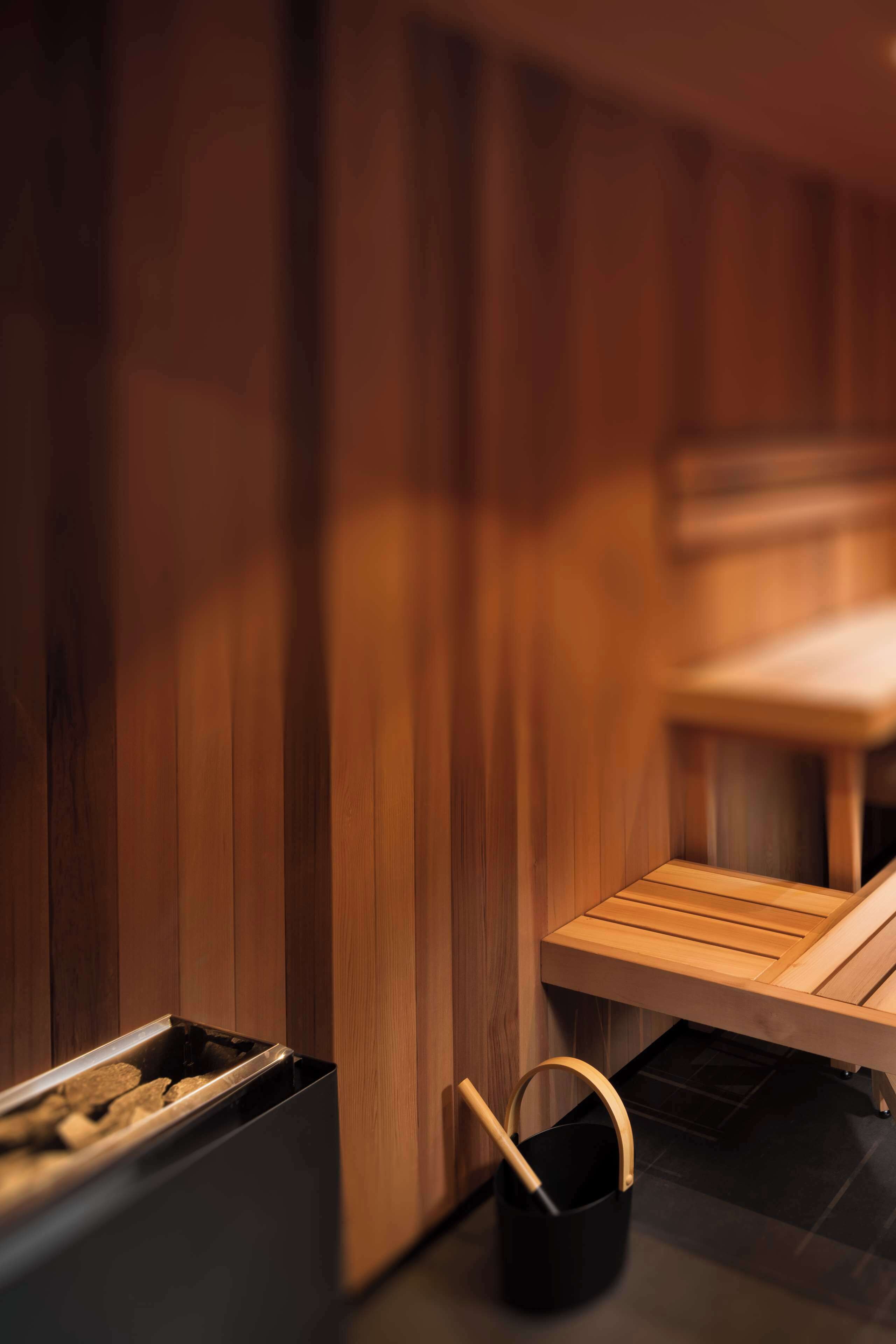 Een sauna met houten wanden, een bank en een emmer.