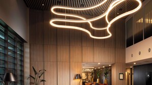 A modern lobby with a curved ceiling light fixture, leather seating, and a central coffee table. - Doubletree By Hilton Hobart (Hobart)