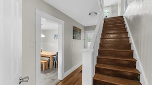 A staircase with wooden steps and white railings, leading to a room with a dining area visible through an open door. - Renovated Central Park Chic (Birmingham)