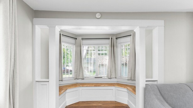 A bay window with white trim, a wooden bench, and a grey armchair. - Renovated Central Park Chic (Birmingham)