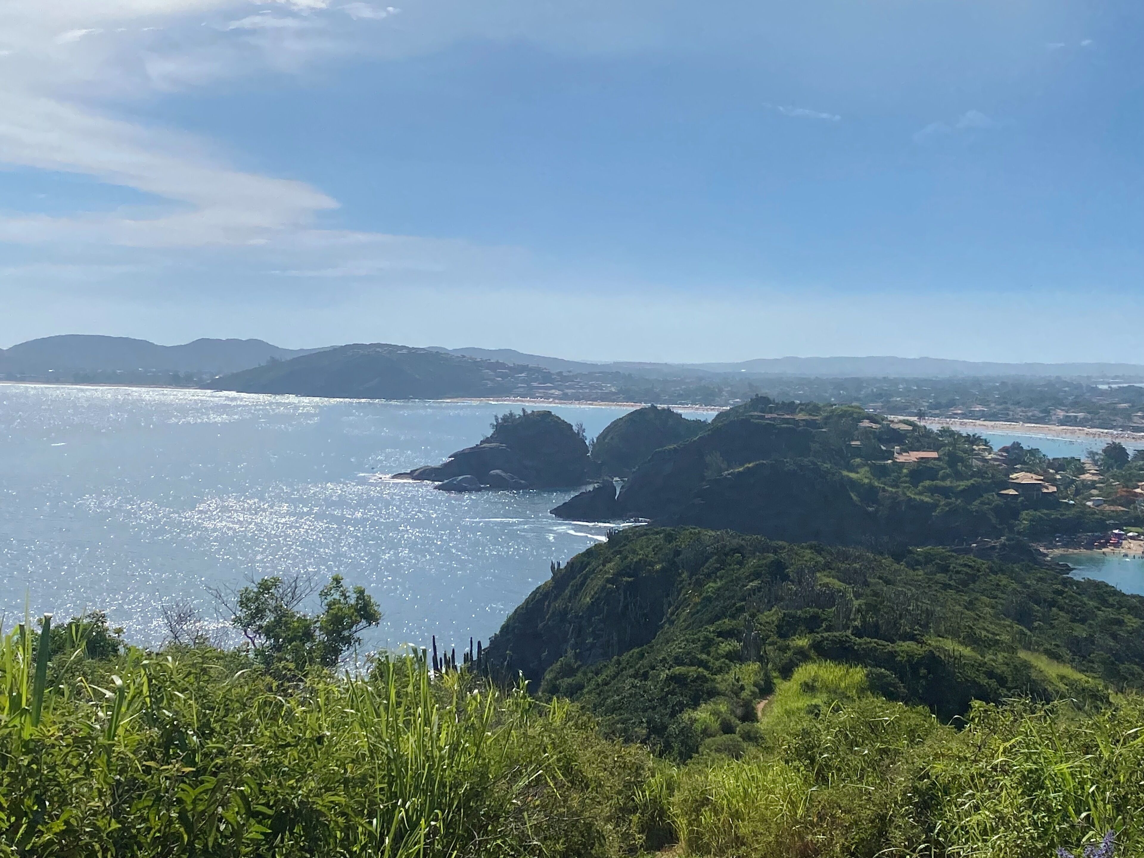 Paisaje costero con vistas despejadas al mar, colinas y una playa distante.