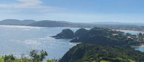 Paisaje costero con vistas despejadas al mar, colinas y una playa distante.