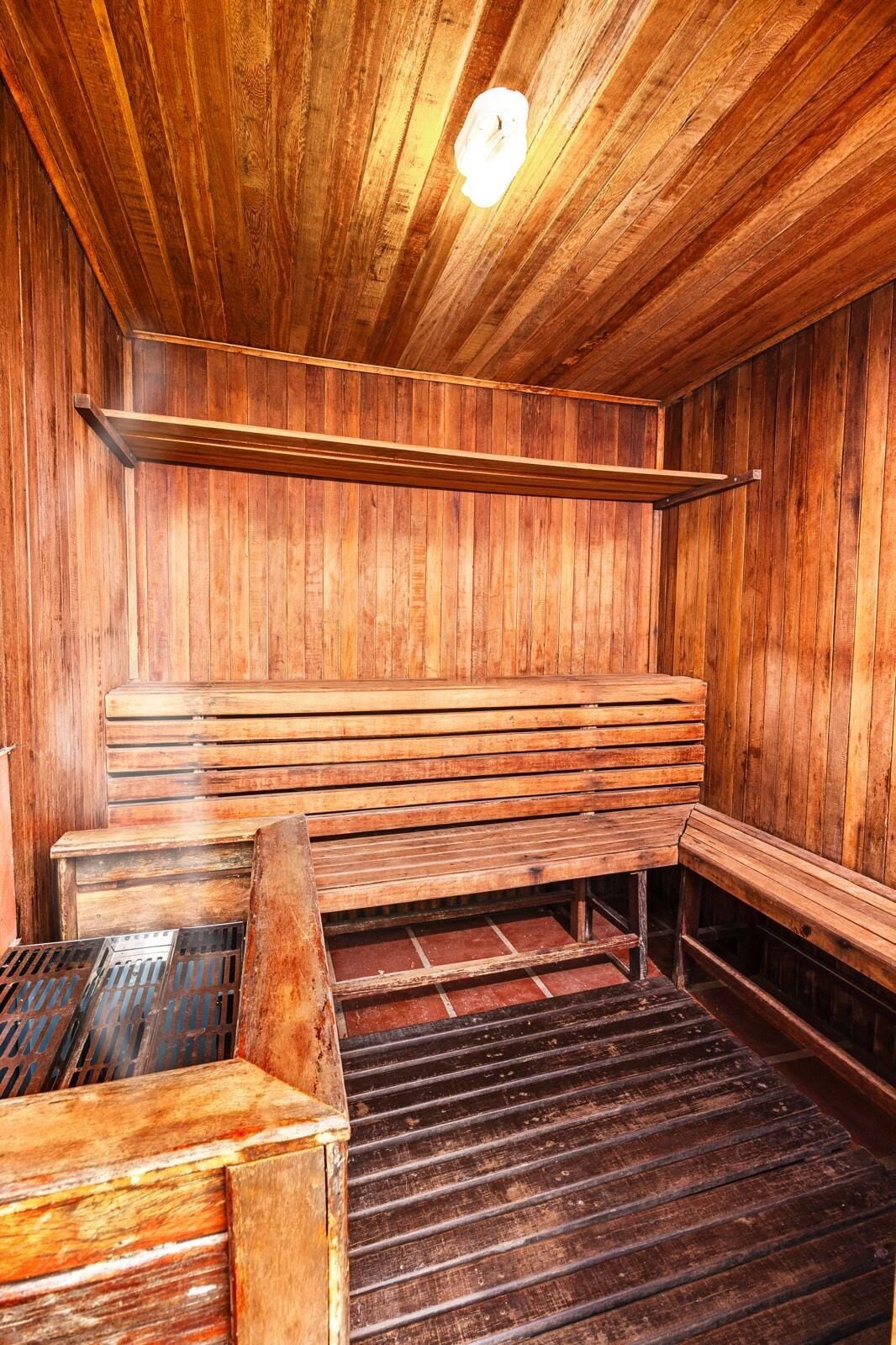 A sauna with wooden benches and a metal grate.