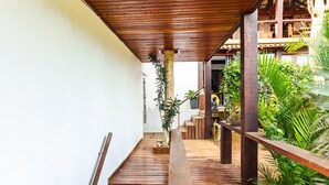 A wooden staircase leading to a covered outdoor area with plants and a seating area. - Maravilha Pousada (Búzios)