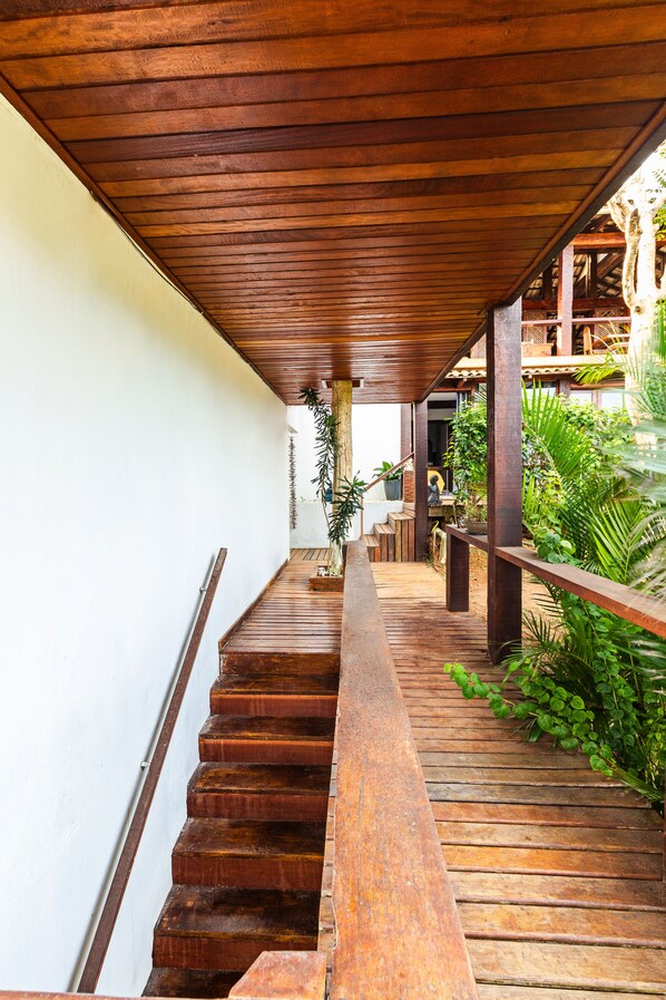 A wooden staircase leading to a covered outdoor area with plants and a seating area. - Maravilha Pousada (Búzios)