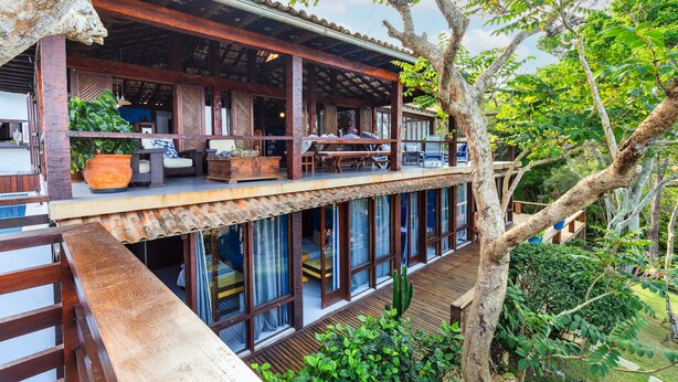 A two-story wooden structure with a balcony, large windows, and a view of the surrounding greenery. - Maravilha Pousada (Búzios)