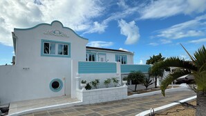 Een wit gebouw met turquoise details, een rond raam en een tegelpad.