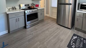 Eine moderne Küche mit grauen Schränken, Edelstahlgeräten und Holzboden.