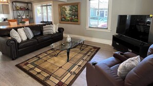 Ein Wohnzimmer mit einem dunkelbraunen Sofa, einem Glastisch und einem Fernseher.