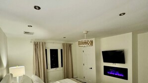 Een moderne slaapkamer met een bed, een televisie en een open haard.
