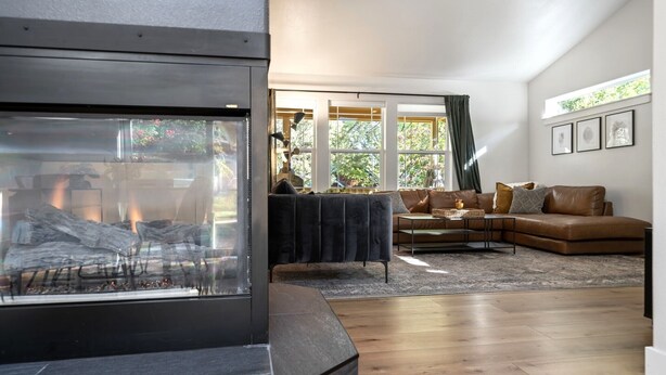Una sala de estar moderna con chimenea, un sofá modular y un ventanal con cortinas.