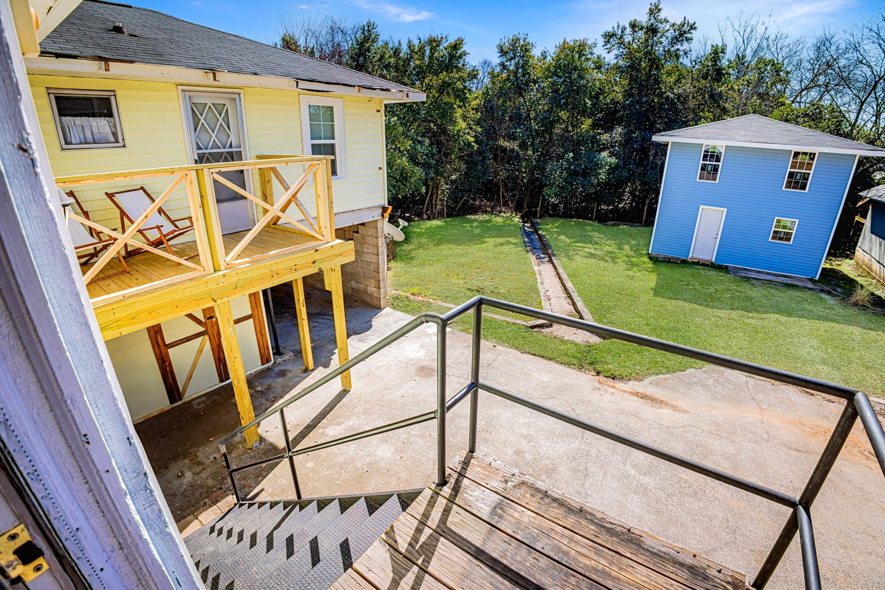 A two-story house with a wooden deck and a small porch.