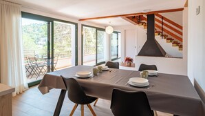 Ein Essbereich mit einem Tisch für vier Personen, großen Fenstern und einer Treppe mit Holzwerteln.