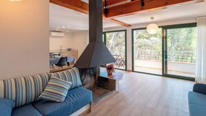A modern living room with a fireplace, a sofa, and a dining area in the background.