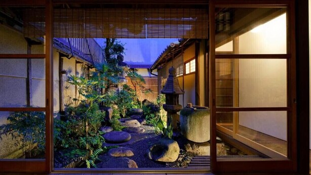A traditional Japanese garden with a wooden floor, stone lantern, and a view through a shoji screen.