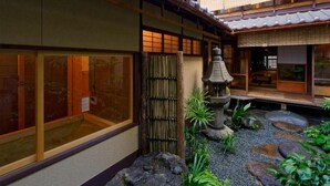 A traditional Japanese courtyard with a stone lantern, bamboo fence, and a small garden with rocks and plants.