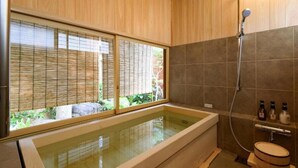 A modern bathroom with a glass-enclosed hot tub, wooden flooring, and a shower area.