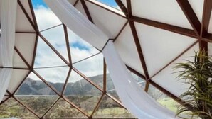Un intérieur moderne aux lignes géométriques, avec un lit et des oreillers, de grandes fenêtres et une vue sur les montagnes.