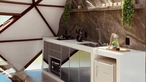 Une cuisine moderne avec un plafond au design géométrique, un mur d’accent en pierre et des appareils électroménagers intégrés.