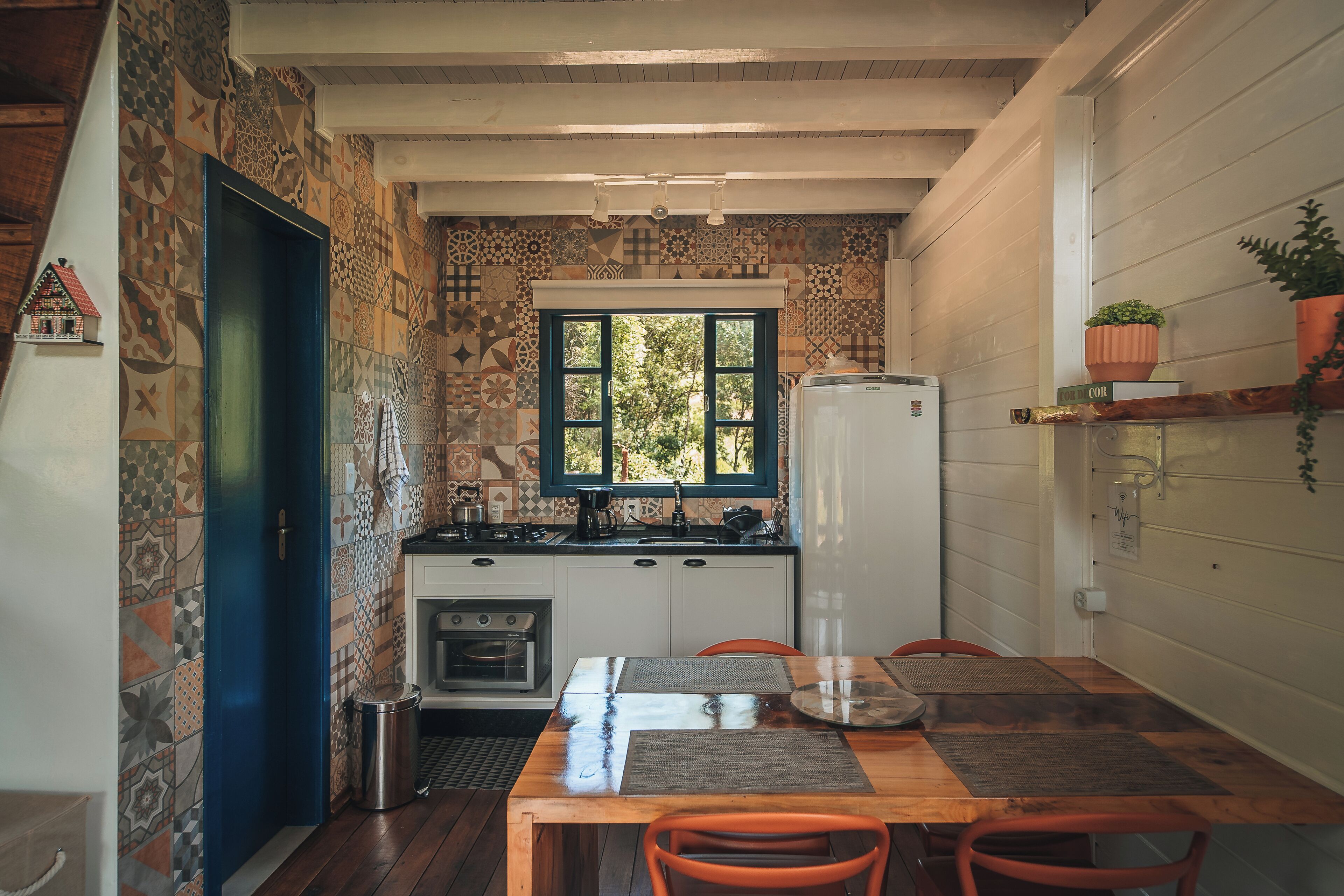 Une cuisine de taille réduite, avec des carreaux décoratifs, une fenêtre et un réfrigérateur.