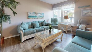 A living room with a sofa, armchairs, a coffee table, and a large window with curtains. - Beach Access Across the Street, Shared Heated Pool (Corpus Christi)