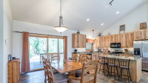A spacious kitchen with wooden cabinets, a central island with bar stools, and a dining area with a large table and chairs.
