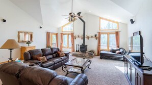 A spacious living room with leather sofas, a glass coffee table, a fireplace, and a television.