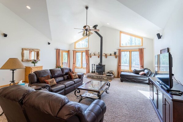 A spacious living room with leather sofas, a glass coffee table, a fireplace, and a television. - Spacious Dog-Friendly Grand Lake House (Grand Lake)