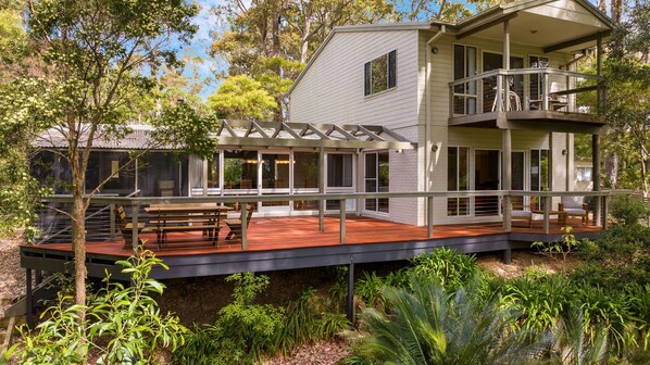 A two-story house with a deck, large windows, and a balcony.