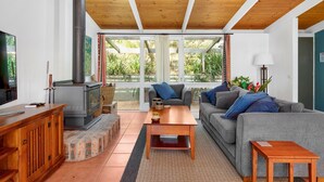 A cozy living room with a fireplace, a sofa, a coffee table, and a television. - Home Sweet Holiday in Lilli Pilli (Lilli Pilli)