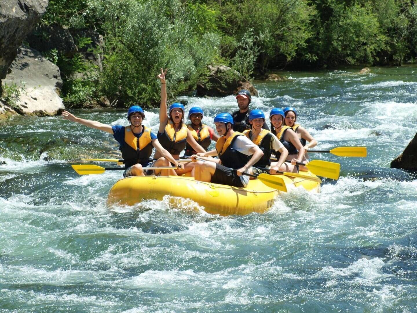 A group of people in a yellow raft navigating a river.
