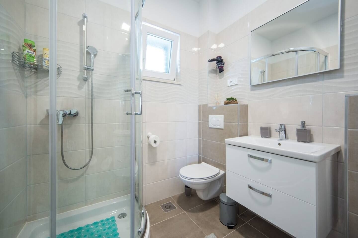 A modern bathroom with a glass-enclosed shower, a toilet, and a vanity with a mirror.