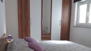 A bedroom with a bed, a nightstand, a lamp, and a window. - Apartments Lavanda & More - One Bedroom Apartment with Shared Terrace (Rab)