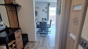 A modern kitchen with wooden cabinets and a black countertop, leading to a dining area with a table and chairs. - Belisima Delux - One Bedroom Apartment With Sea View (Rab)