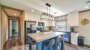 A modern kitchen with a central island, stainless steel appliances, and a large window providing natural light. - Pet-Friendly Hill Country Hideaway w/ Deck (Yancey)