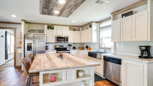A modern kitchen with white cabinetry, stainless steel appliances, and a wooden island.