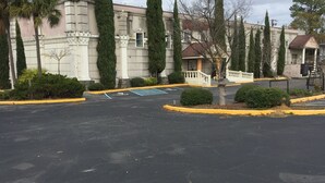 Un estacionamiento con un edificio de arquitectura clásica, que incluye columnas y un pórtico.