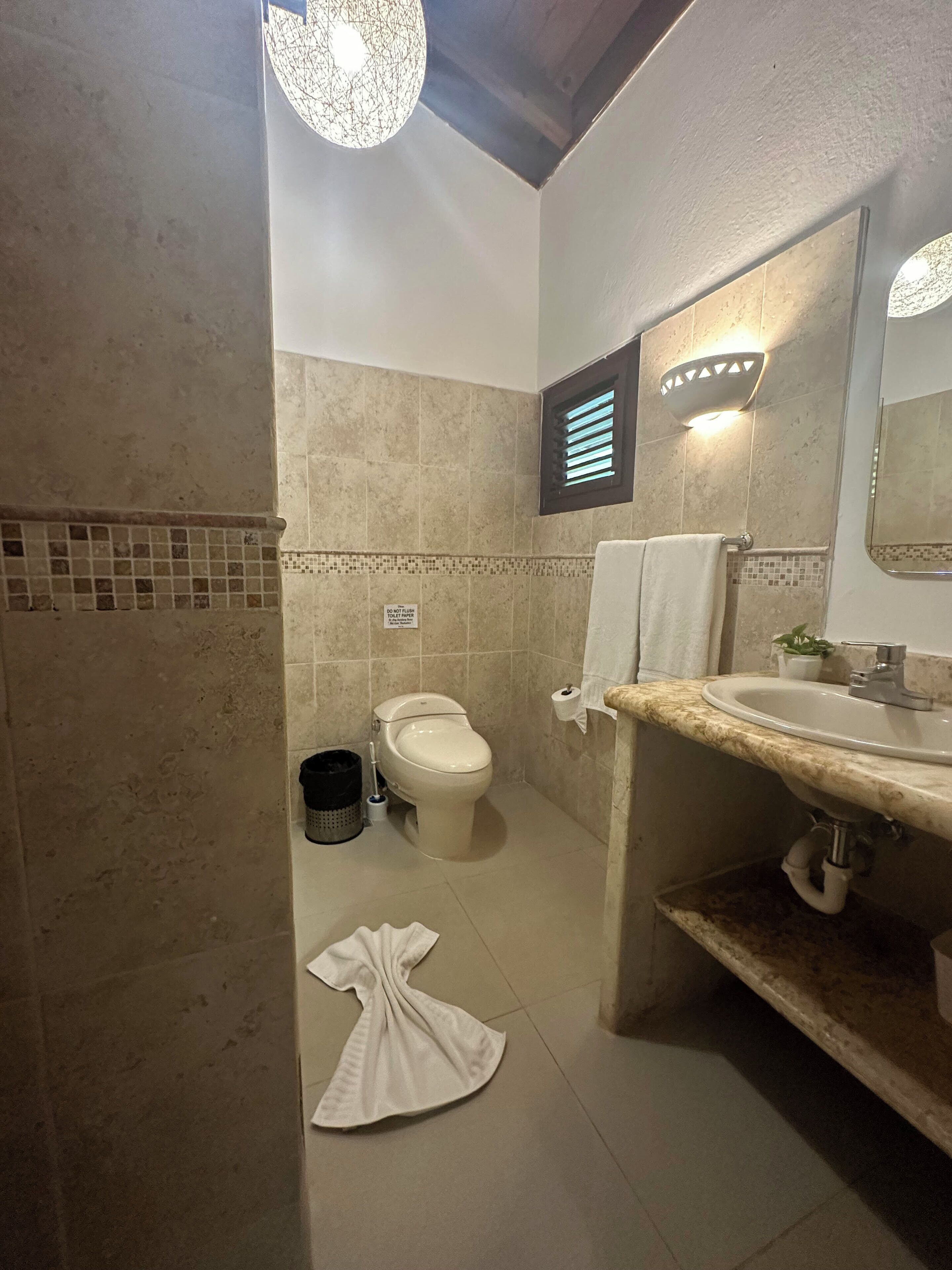 Un baño con inodoro, lavamanos y una toalla en el suelo.