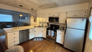 A compact kitchen with white cabinets, a stainless steel refrigerator, a microwave, and a stove. - Alumni Corner

 (State College)