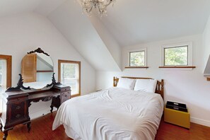 Relax in this spacious bedroom with a large bed, wooden headboard, and two windows.