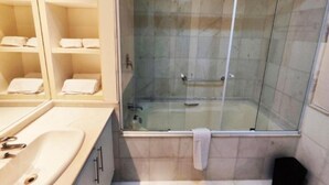 Ein Badezimmer mit einer Duschkabine, einem Waschbecken und Regalen mit Handtüchern.