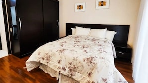 Ein Schlafzimmer mit einem Bett, einem Kleiderschrank und zwei gerahmten Bildern an der Wand.